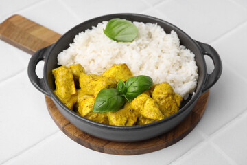 Delicious rice and chicken with curry sauce on white tiled table, closeup