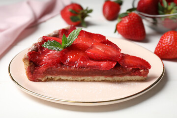 Piece of delicious strawberry tart with mint on white wooden table, closeup