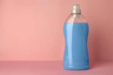 Bottle of fabric softener on pink background, space for text