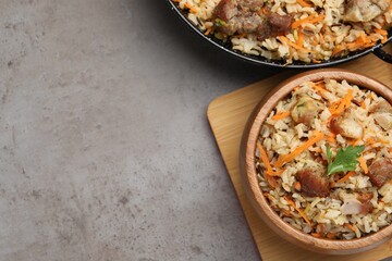 Delicious pilaf with meat and carrot on grey textured table, flat lay. Space for text