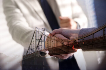 Support or partnership concept. Double exposure with bridge and photo of businesspeople shaking...