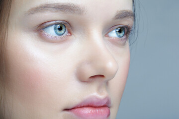Closeup macro shot of human female face. Woman with blue eyes and natural face beauty makeup