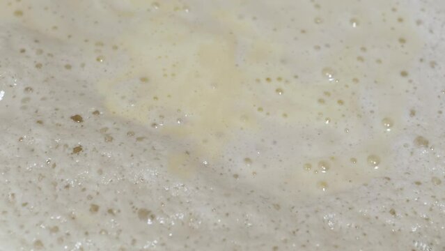 Close up, Fermentation, Sourdough, Air Bubbles on the Surface of Yeast Dough. Texture, backgrounds. Structure. Hole. Live growing yeast, organism. Cooking bread, pastries buns Sweet pastry