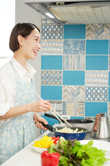 自宅で野菜炒めをする女性