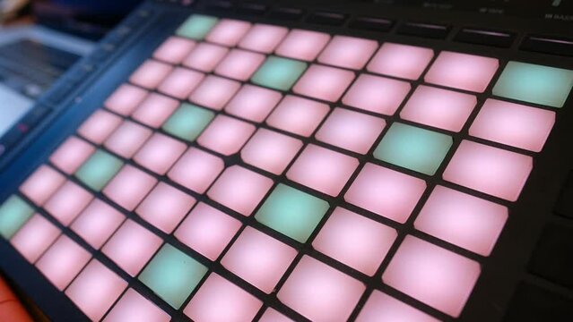 Vibrant music launchpad: closeup view of pink and mint green lights on launchpad while vibrant green light sparking