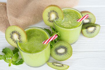 Kiwi yogurt fruit juice smoothie and green kiwi juice drink healthy, delicious taste in a glass for weight loss on a white wooden background.