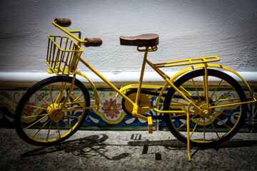 Vintage metal yellow bicycle toy with wooden elements on a shelf as a home decor