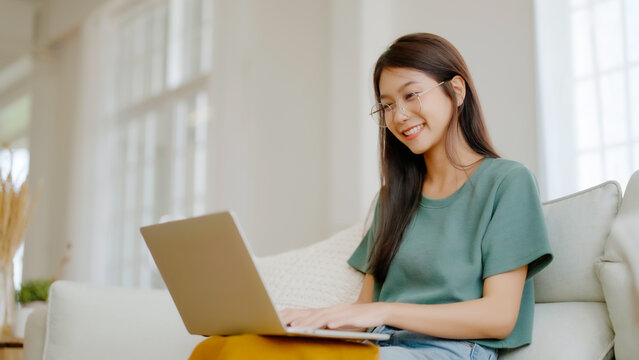 Smiling young asian woman working on laptop at home. Attractive asia female using computer remote studying, watching online education and video calling