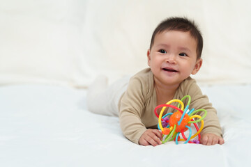 infant baby playing with colorful rubber bites toy on bed