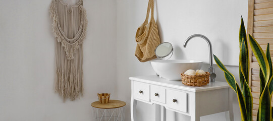 Interior of light bathroom with sink and table