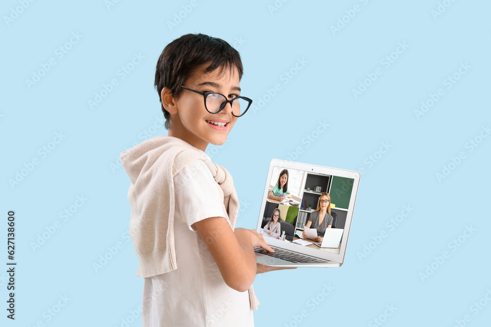 Wall mural Little boy in eyeglasses and with laptop on light blue background. Concept of online education - Wall murals