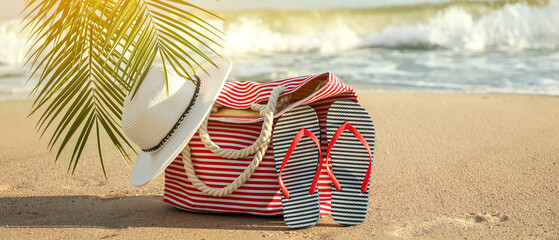 Beach bag with hat and flip-flops on sea coast at tropical resort