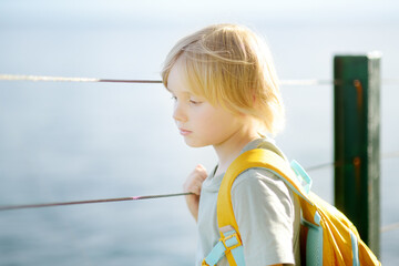 Close up portrait of upset child with satchel. Sad boy don't want to go to school. Kid's fear....