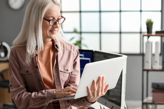 Mature female programmer working with laptop in office