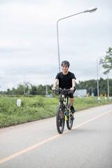 Obraz premium Shot of happy asian guy enjoying biking in the summer park. Sport, leisure and healthy lifestyle concept