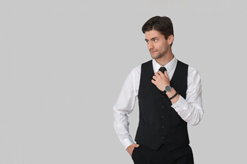 Handsome young businessman with wristwatch on grey background