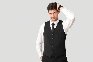 Handsome young businessman with wristwatch on grey background