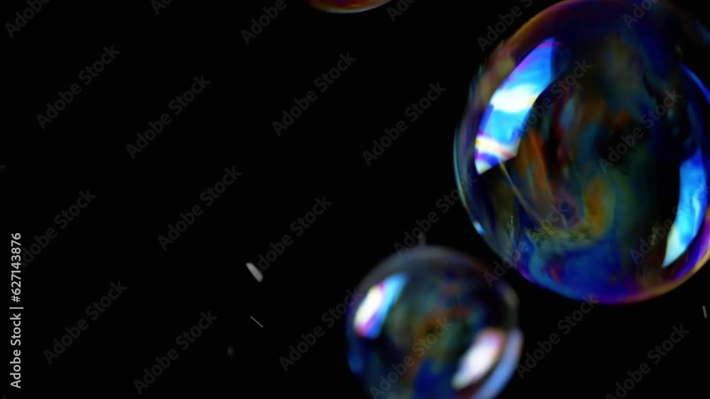 Poster colorful soap bubbles fly in an empty space on isolated black background. many large, small rainbow 