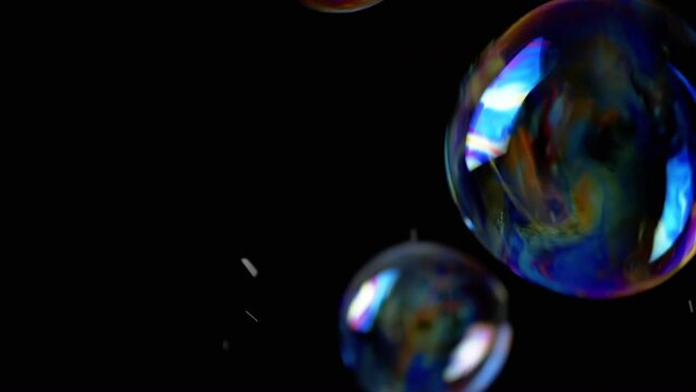 Colorful Soap Bubbles Fly in an Empty Space on Isolated Black Background. Many large, small rainbow bubbles randomly rotate, float, fall, bursts. Blurred motion. Focus. Abstract. Slow motion. Splash.