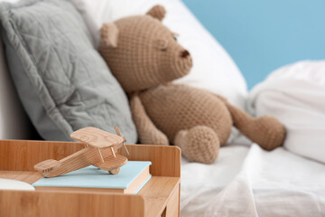 Fototapeta na wymiar Wooden toy airplane and books on bedside table in children's bedroom, closeup