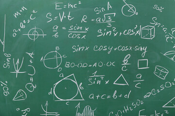 Different drawn geometric figures and math formulas on green chalkboard