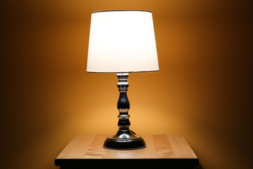 Glowing lamp on wooden table in dark room