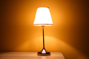 Glowing lamp on wooden table in dark room