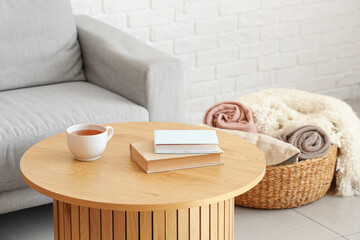 Cup of tea and books on table in light living room, closeup