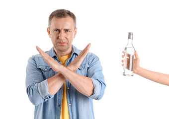 Displeased mature man rejecting bottle of vodka on white background
