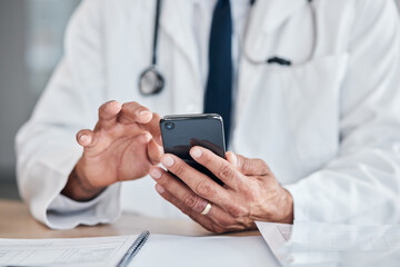 Smartphone, hands and doctor typing at table in hospital for research, telehealth or healthcare. Phone, medical professional or surgeon, expert or person on wellness app, email or online consultation