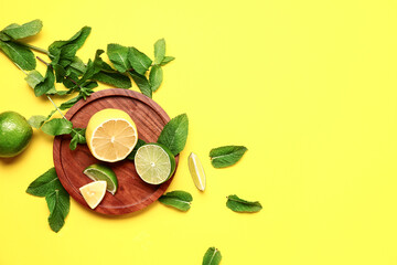 Wooden plate with lime, lemon and fresh mint leaves on yellow background