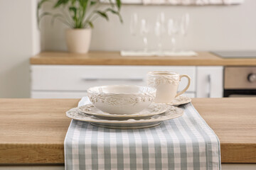 Clean plates, bowl and cup on wooden kitchen countertop, closeup