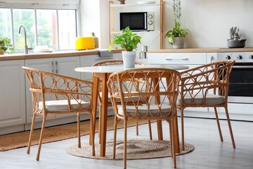 Interior of light kitchen with white counters, dining table and big window