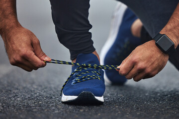 Man, hands and tie shoes on road for running, fitness or cardio workout on asphalt in the outdoors....