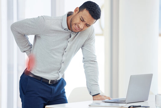 Businessman, laptop and back pain in burnout, stress or inflammation and mental health by office desk. Fatigue or tired man with painful area from accident, rear ache or bad posture at the workplace