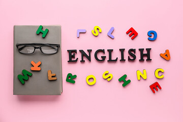 Word ENGLISH with eyeglasses, notebook and wooden letters on pink background