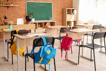 Interior of stylish empty classroom with backpacks and stationery