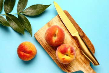 Wooden board with sweet peaches on blue background