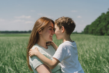 Happy Mother's Day. Little boy and mother is playing in a green barley field. People and nature. Rural scene