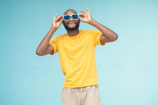 Sunglasses, black man and fashion on a blue background with cool and trendy style with mock up space. Young model person with eyewear in studio for advertising designer brand, logo or color in hands