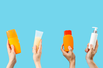 Female hands with bottles of sunscreen cream on blue background