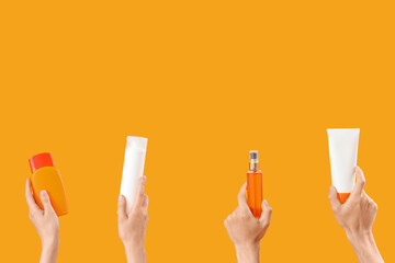 Female hands with bottles of sunscreen cream on yellow background