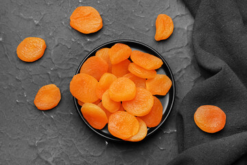 Tray with tasty dried apricots on black background