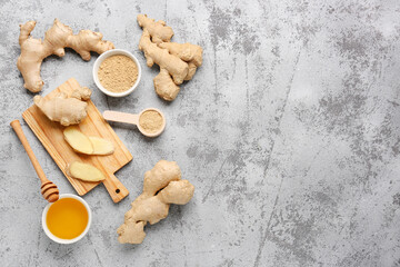 Fresh ginger roots, bowl and wooden spoon with dried powder on blue background