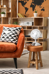 Interior of stylish living room with sofa and electric fan on stool