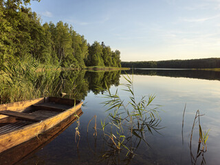 Fototapeta na wymiar A wooden boat on a calm lake. In the evening. Lithuania