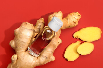 Bottle of ginger cosmetic oil on red background
