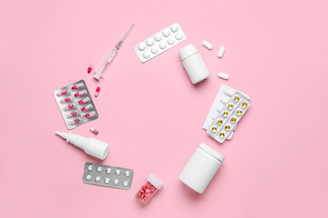 Frame made of different pills, syringe and bottles of medicines on pink background