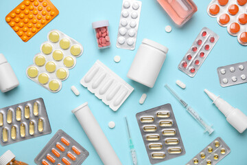 Different pills, syringe and bottles of medicines on blue background