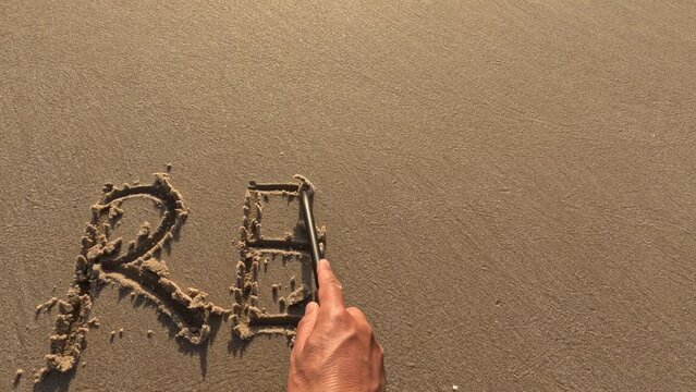 The word  "Relax" written by hand on the beach sand, enjoying outdoor summer activity,